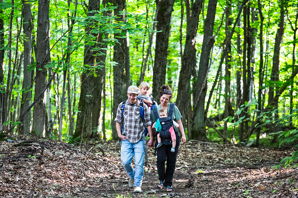 Two parents and two kids on a hike in the forest at Ciel et Bois